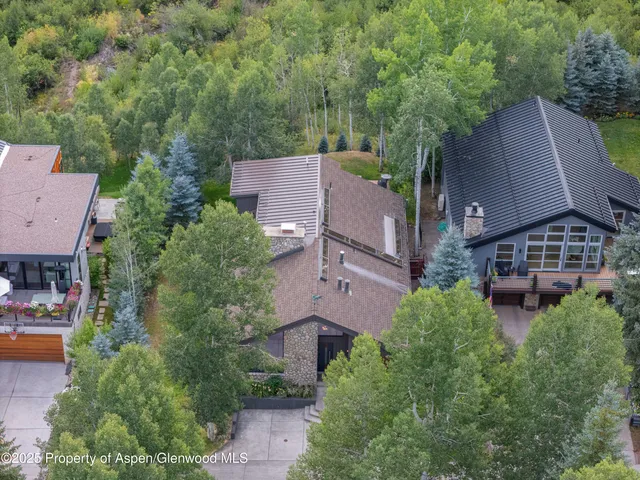 an aerial view of a house with outdoor space and trees all around