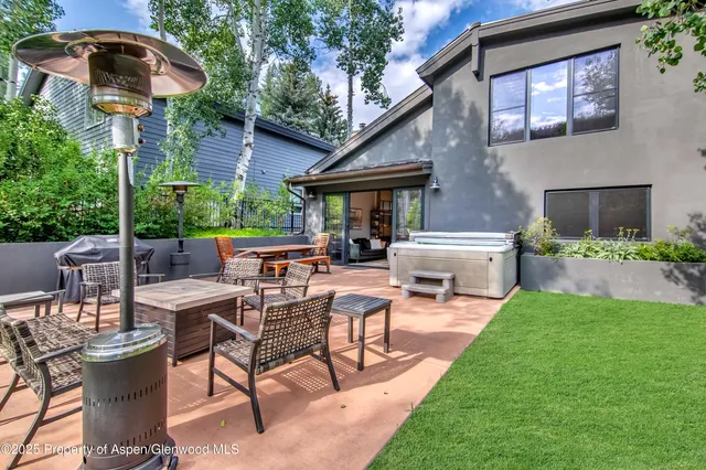 a view of a patio with table and chairs under an umbrella with a fire pit