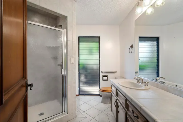 a bathroom with a granite countertop shower sink vanity and mirror