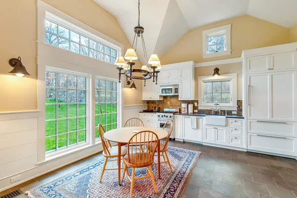 a dining room with wooden floor a chandelier a wooden table and chairs