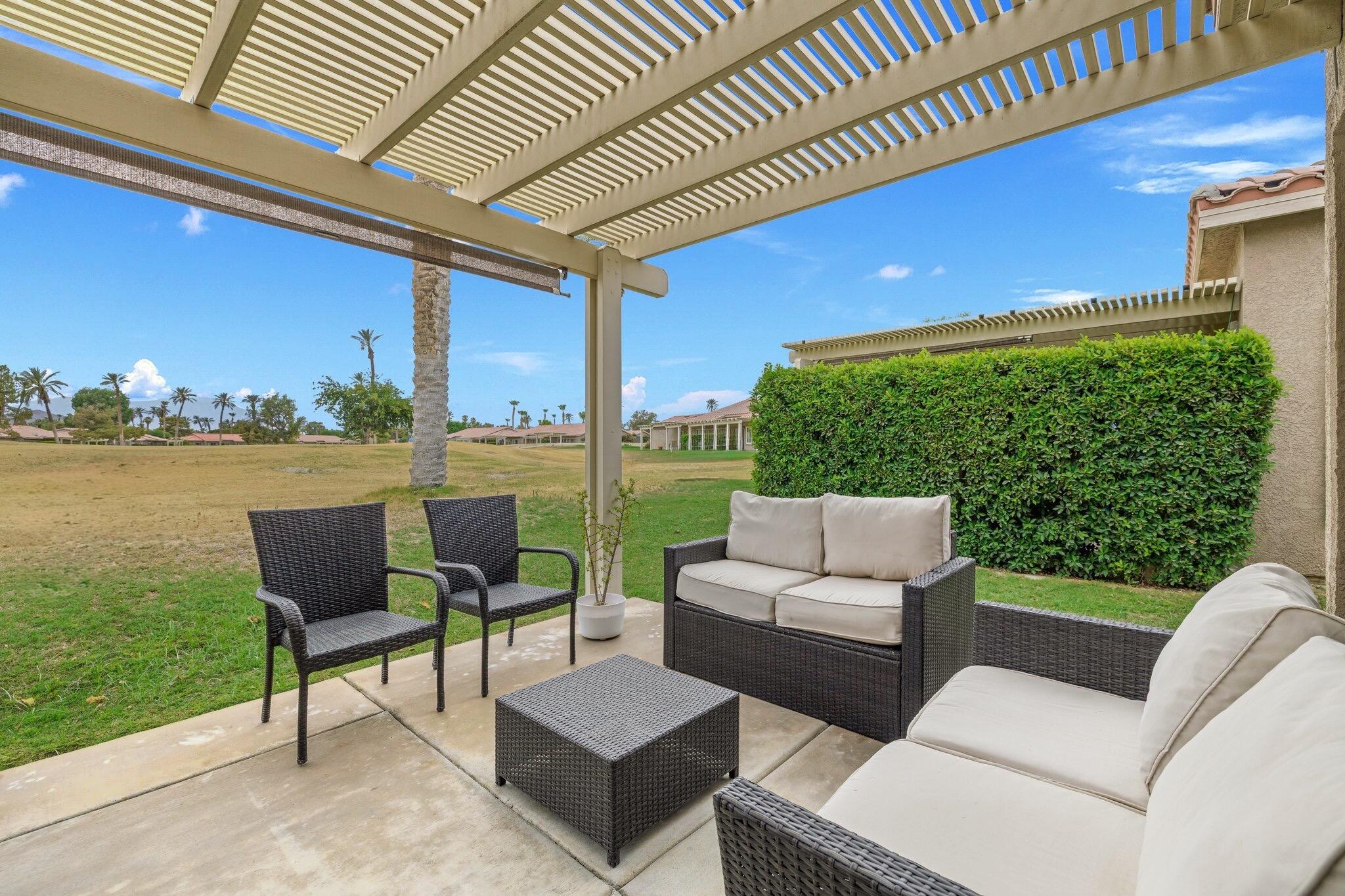 a view of a patio with couches dining table and chairs with wooden floor next to a yard