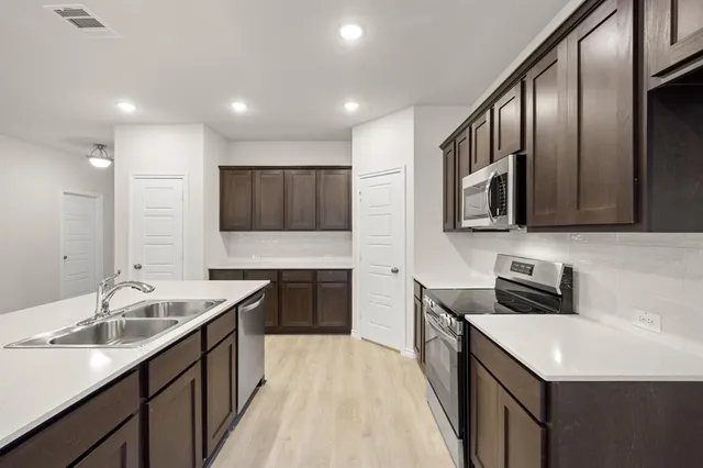a kitchen with stainless steel appliances wooden cabinets a stove a microwave and a sink
