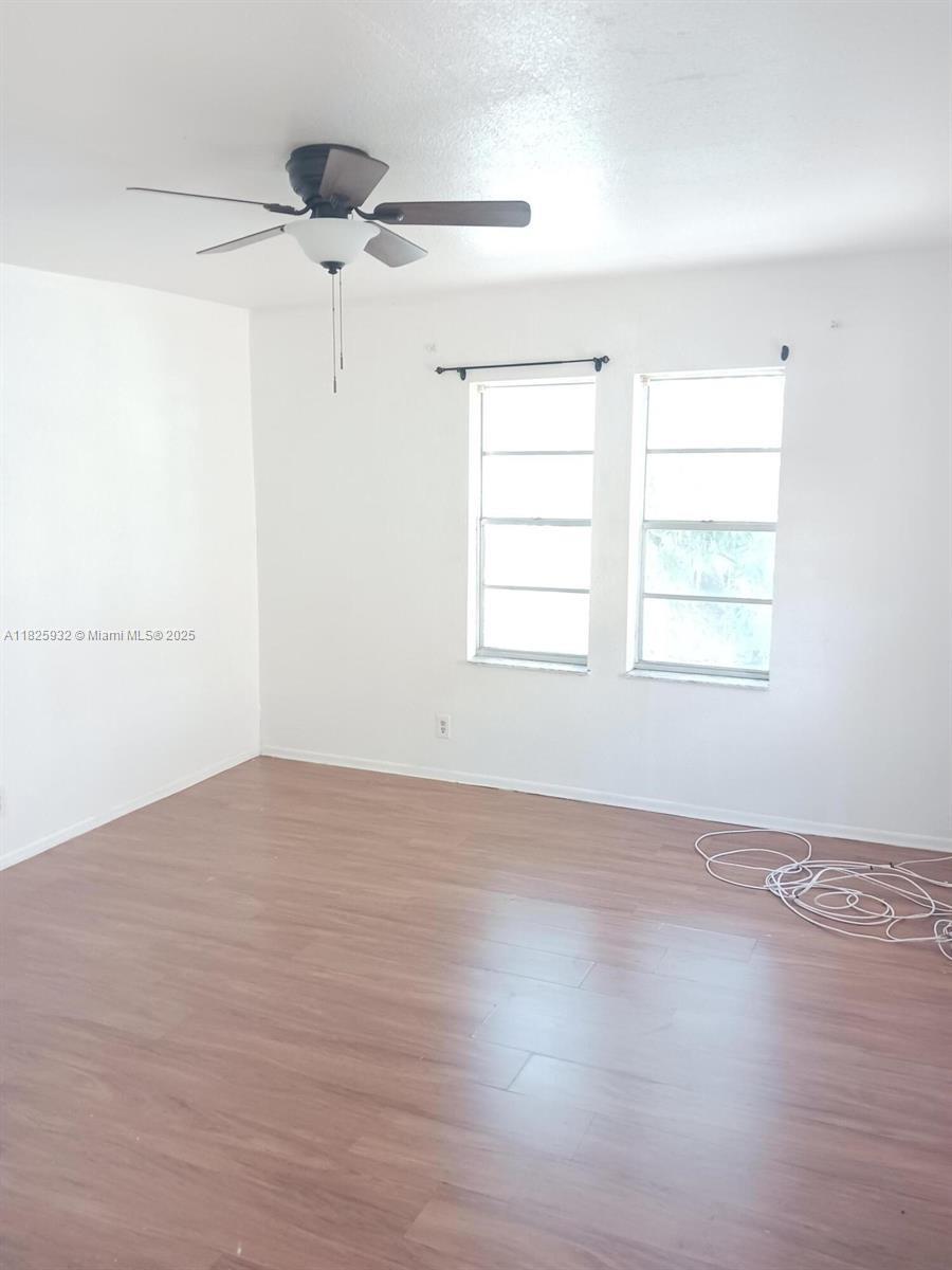 706 9th Street, Unit 2 West Palm Beach, FL 33401 - Photo 6 of 9 an empty room with wooden floor fan and windows
