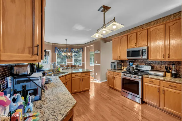 a large kitchen with stainless steel appliances granite countertop a stove and a wooden floors