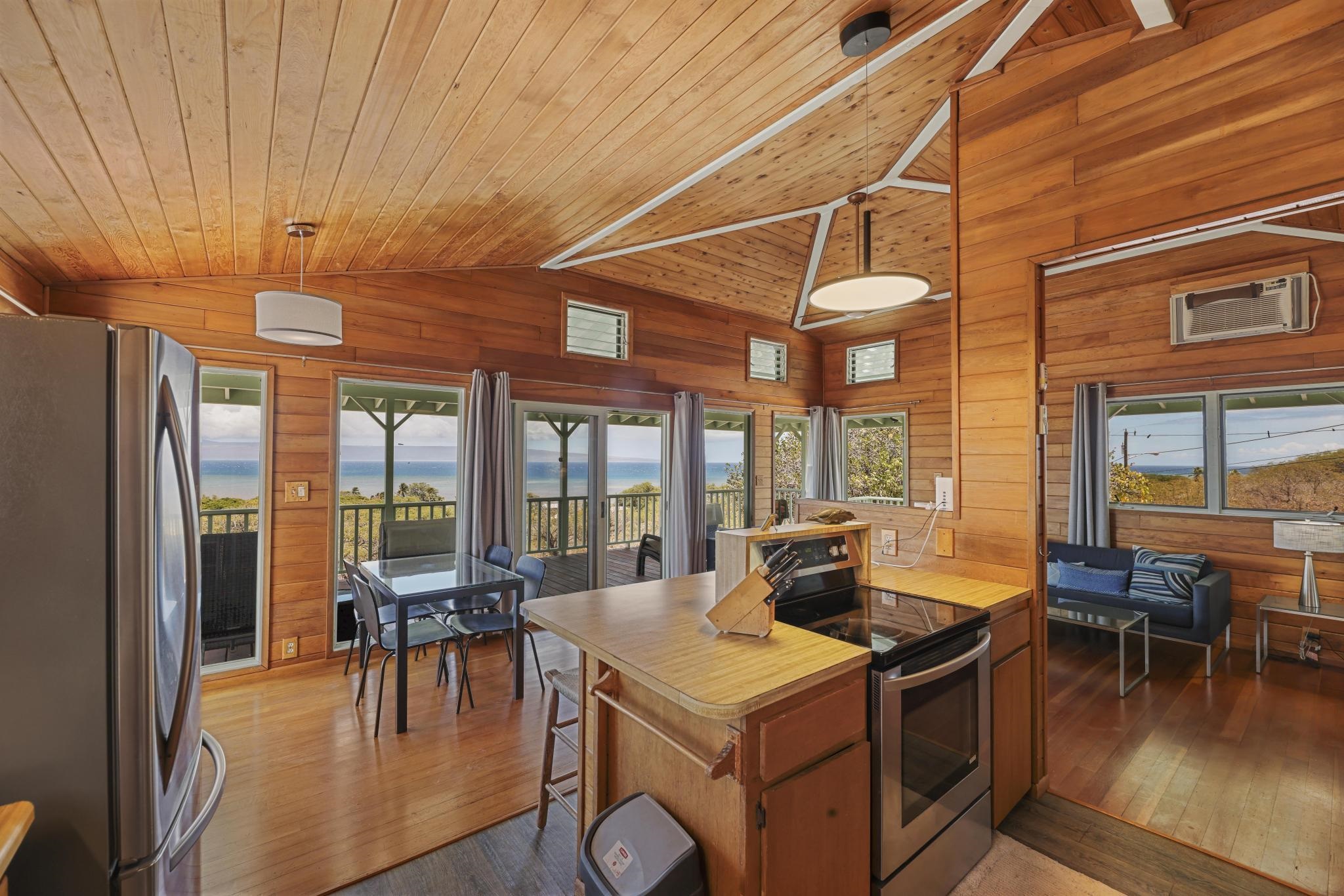 122 Ulua Road Kaunakakai, HI 96748 - Photo 40 of 48 a kitchen with stainless steel appliances granite countertop a stove a refrigerator a dining table and chairs with wooden floor