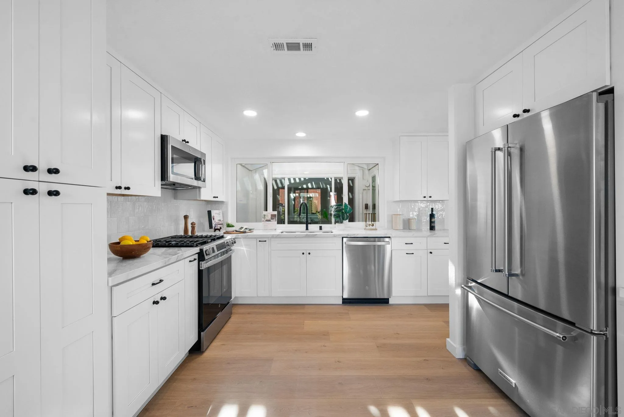 4975 Delos Way Oceanside, CA 92056 - Photo 8 of 31 a kitchen with white cabinets and stainless steel appliances