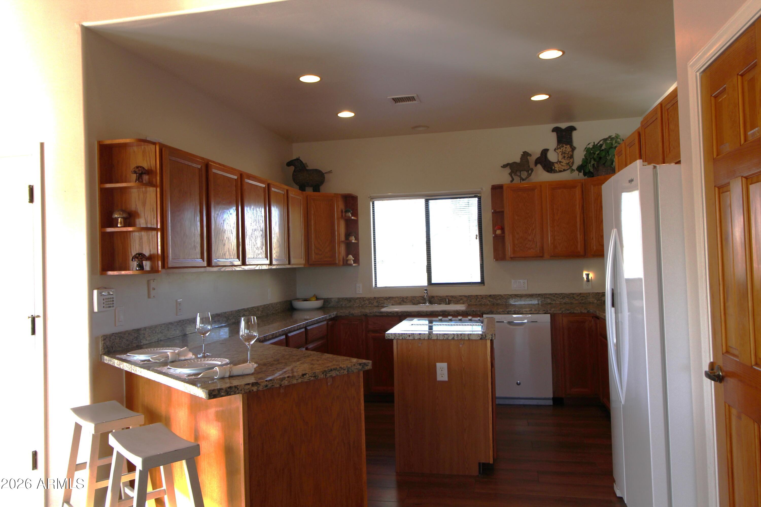 1405 East Circle Mountain Road New River, AZ 85087 - Photo 13 of 40 a kitchen with kitchen island granite countertop a sink cabinets and stainless steel appliances