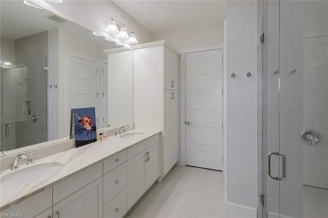 a spacious bathroom with a double vanity sink a large mirror and shower