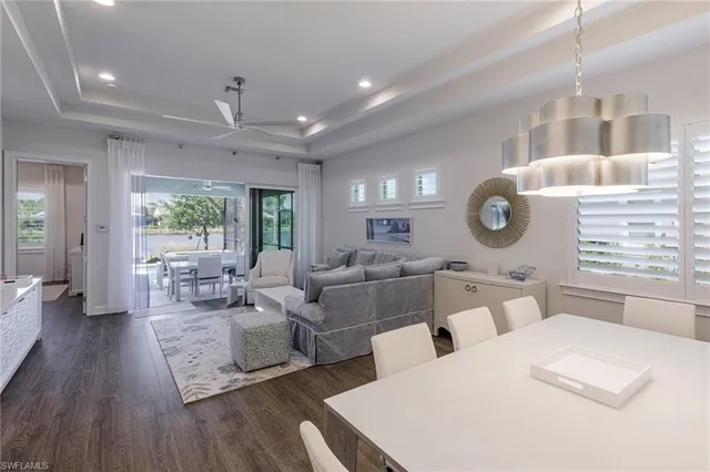 a living room with lots of white furniture and wooden floor