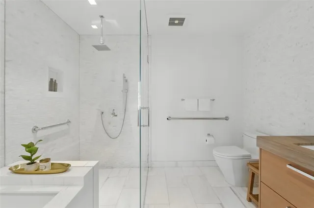 a bathroom with a granite countertop sink a toilet and a shower