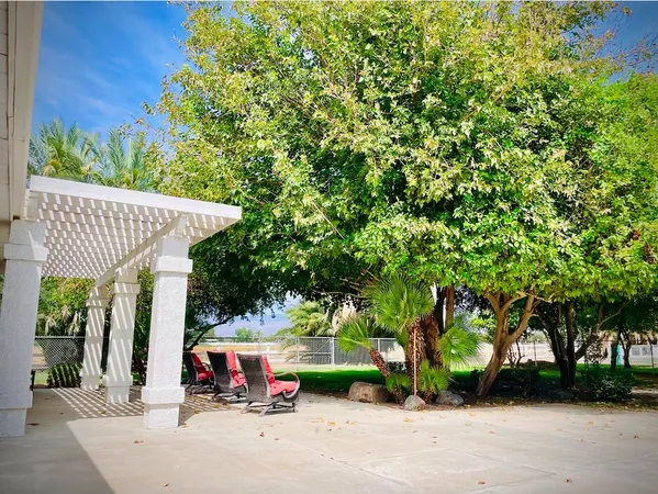 a view of a patio with table and chairs and a large tree