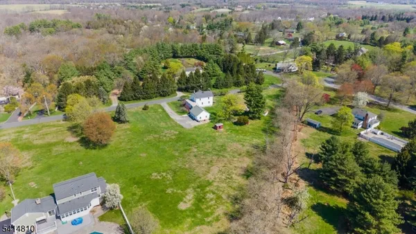 an aerial view of residential houses with outdoor space and trees