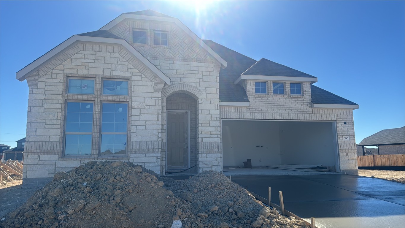 View of front facade with stone siding, concrete driveway, and an attached garage