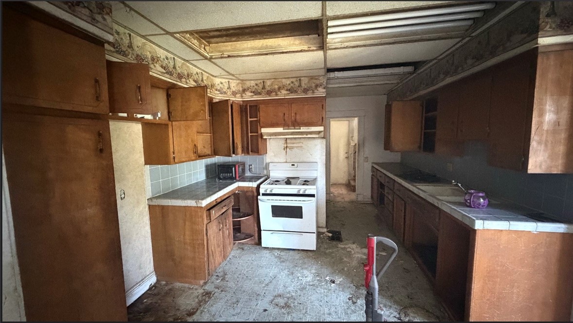 127 West 21st Street Merced, CA 95340 - Photo 5 of 5 a kitchen with stainless steel appliances granite countertop a refrigerator a stove and a sink with wooden cabinets