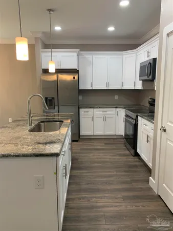 a large kitchen with stainless steel appliances granite countertop a stove a sink dishwasher a microwave oven and a refrigerator with wooden floor