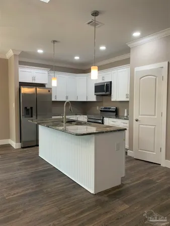 a kitchen with stainless steel appliances granite countertop a sink a stove a refrigerator and a oven with wooden floor