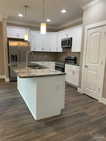 a kitchen with kitchen island granite countertop a sink a counter top space appliances and cabinets