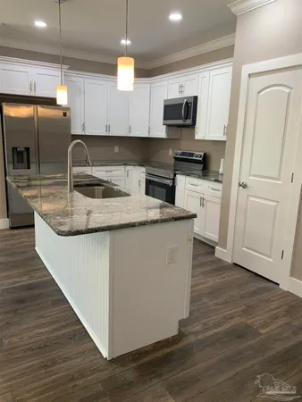 a kitchen with granite countertop a sink a stove and cabinets