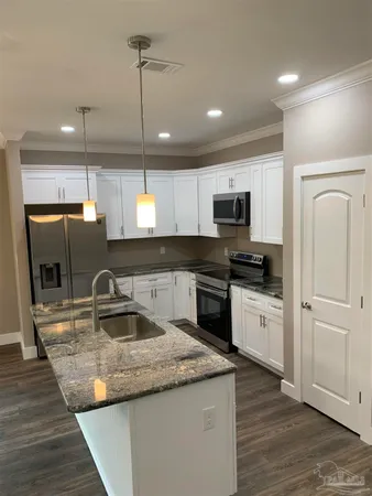 a kitchen with stainless steel appliances granite countertop a refrigerator a stove a sink and a microwave