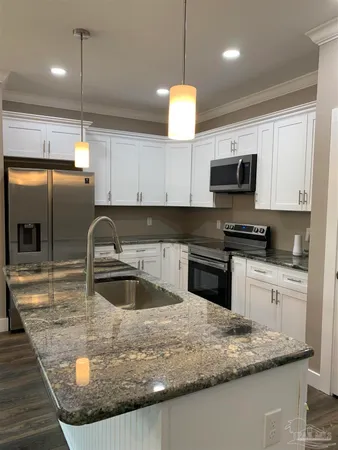 a kitchen with stainless steel appliances granite countertop a refrigerator a sink and a stove