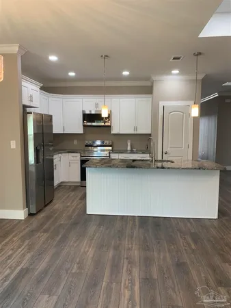 a large kitchen with stainless steel appliances kitchen island granite countertop a stove a refrigerator a sink a microwave and wooden floor