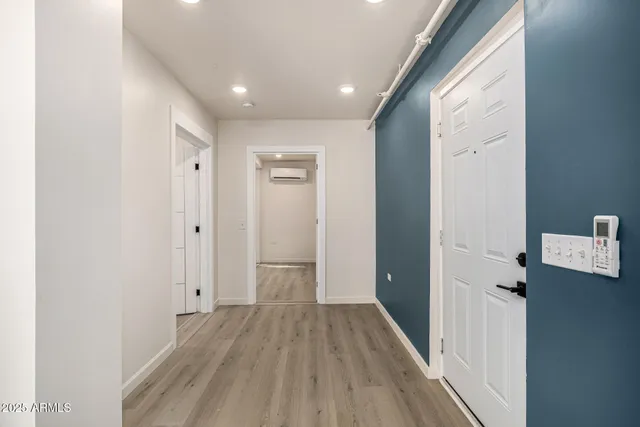 a view of a hallway with wooden floor and a bathroom