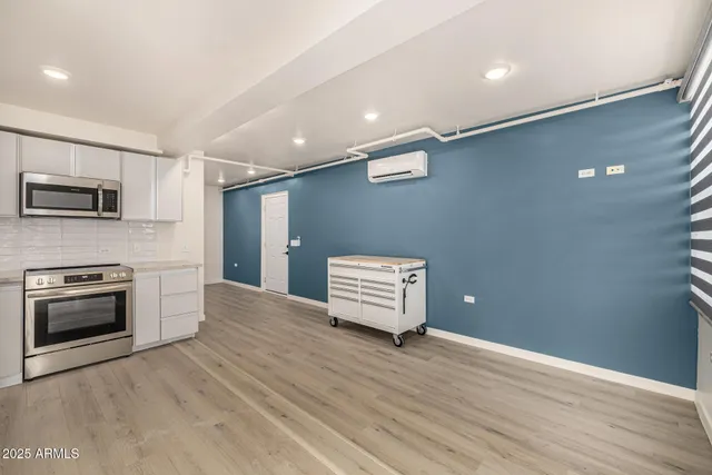 a view of an empty room with wooden floor and a kitchen