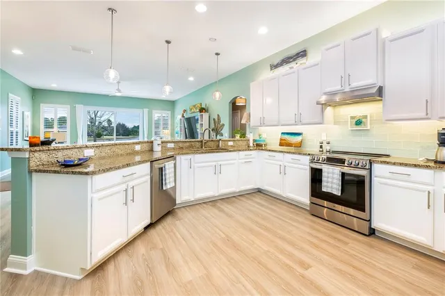 a kitchen with stainless steel appliances white cabinets and wooden floors