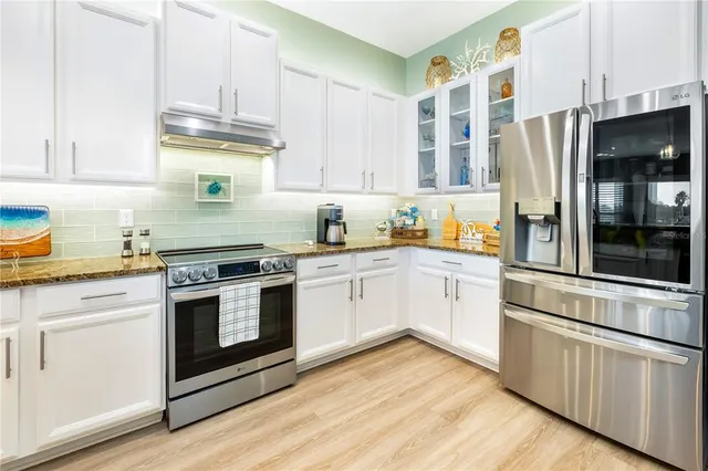a kitchen with stainless steel appliances kitchen island granite countertop a table chairs and a refrigerator