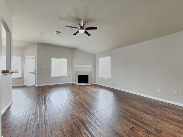 a view of an empty room with wooden floor and a window