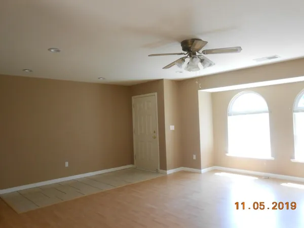 an empty room with windows and fan