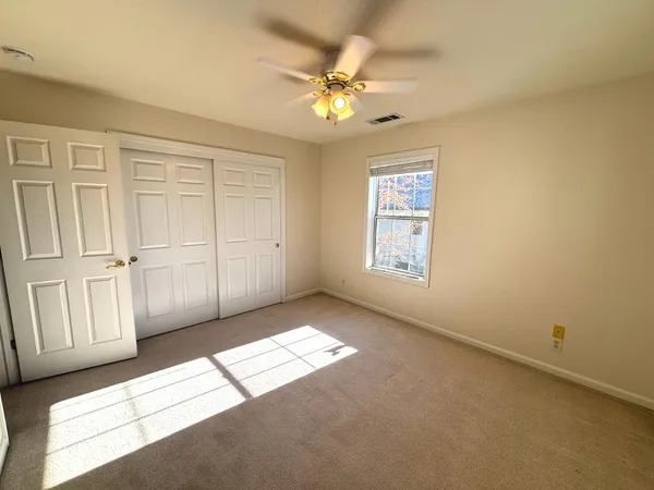 an empty room with windows and ceiling fan