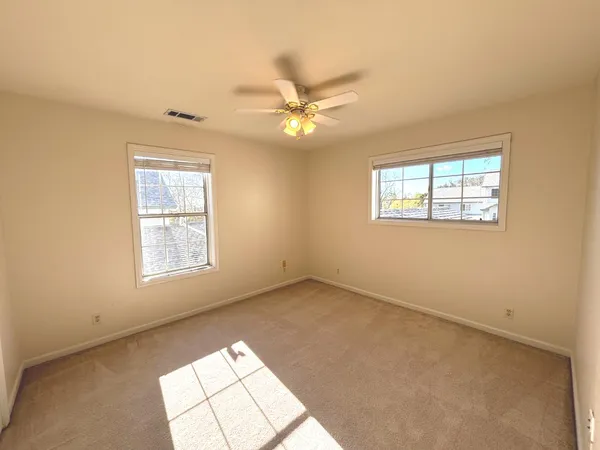 an empty room with windows and fan