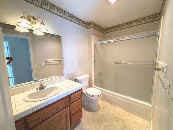 a bathroom with a sink a toilet a mirror and shower