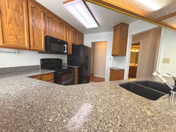 a kitchen with stainless steel appliances kitchen island granite countertop a refrigerator a stove top oven and sink