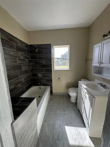 a bathroom with a granite countertop sink a toilet and bathtub