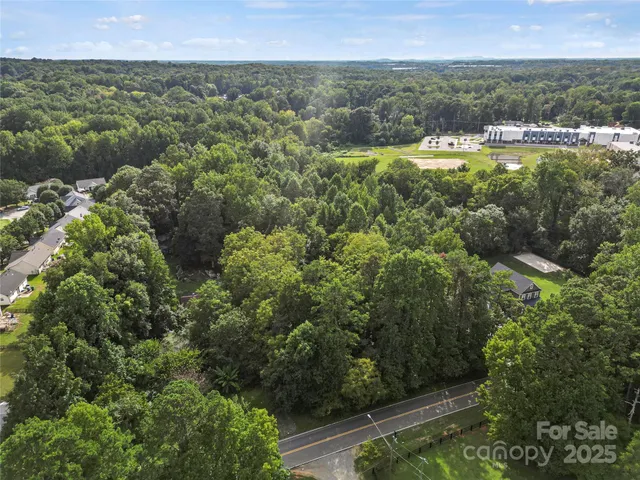 an aerial view of residential houses with outdoor space and trees