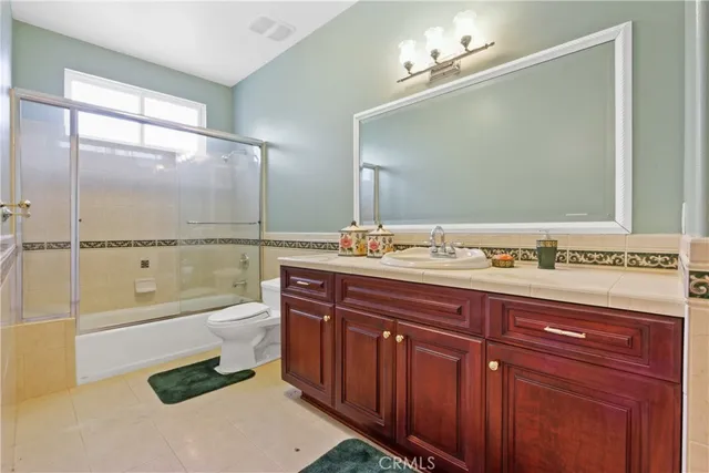 a bathroom with a granite countertop sink a toilet a mirror and bathtub