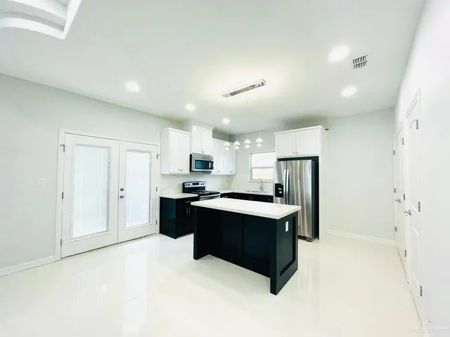 a kitchen with stainless steel appliances a sink a stove a refrigerator and cabinets