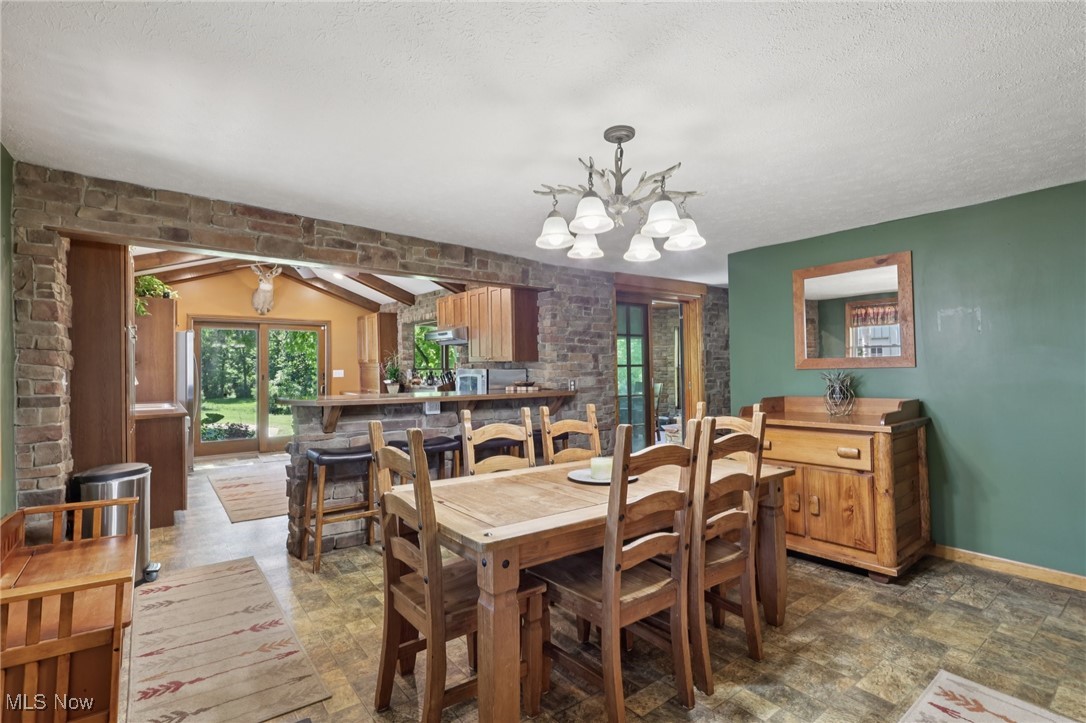 6414 Tennant Road Collins, OH 44826 - Photo 14 of 50 Dining area featuring beamed ceiling, a chandelier, stone finish floors, and a textured ceiling
