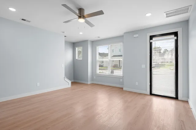 an empty room with wooden floor and windows