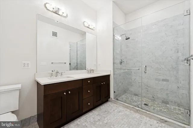 a bathroom with a double vanity sink toilet and shower