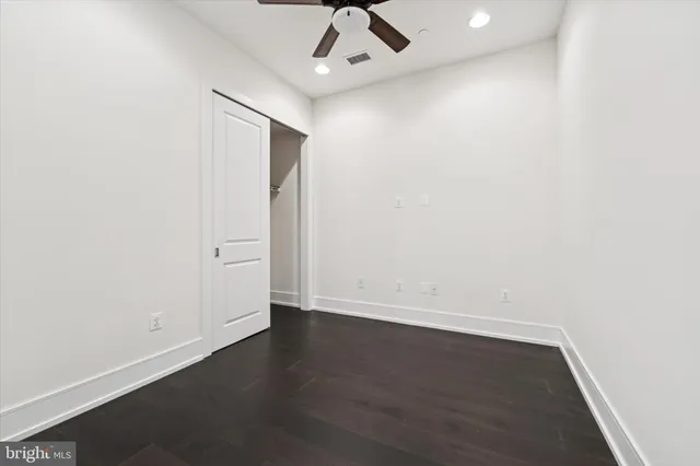 an empty room with wooden floor and ceiling fan