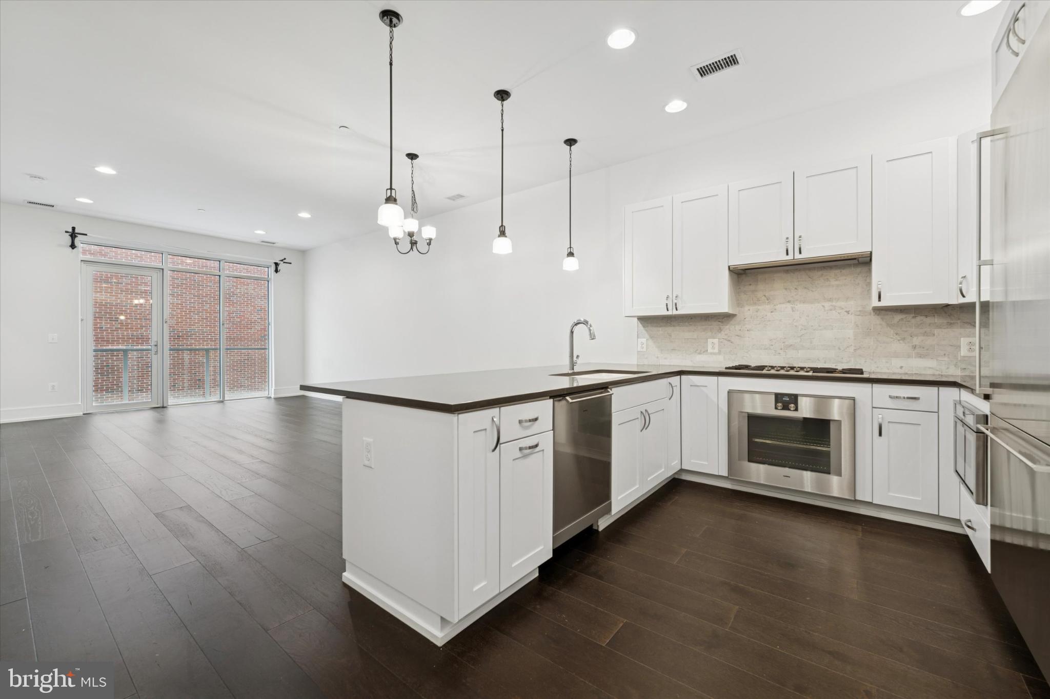 410 South Front Street, Unit 313 Philadelphia, PA 19147 - Photo 2 of 24 a kitchen with stainless steel appliances granite countertop a stove a sink a refrigerator white cabinets and wooden floor next to a window