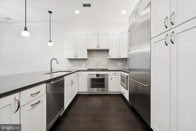 a kitchen with stainless steel appliances granite countertop a sink a stove a refrigerator and cabinets