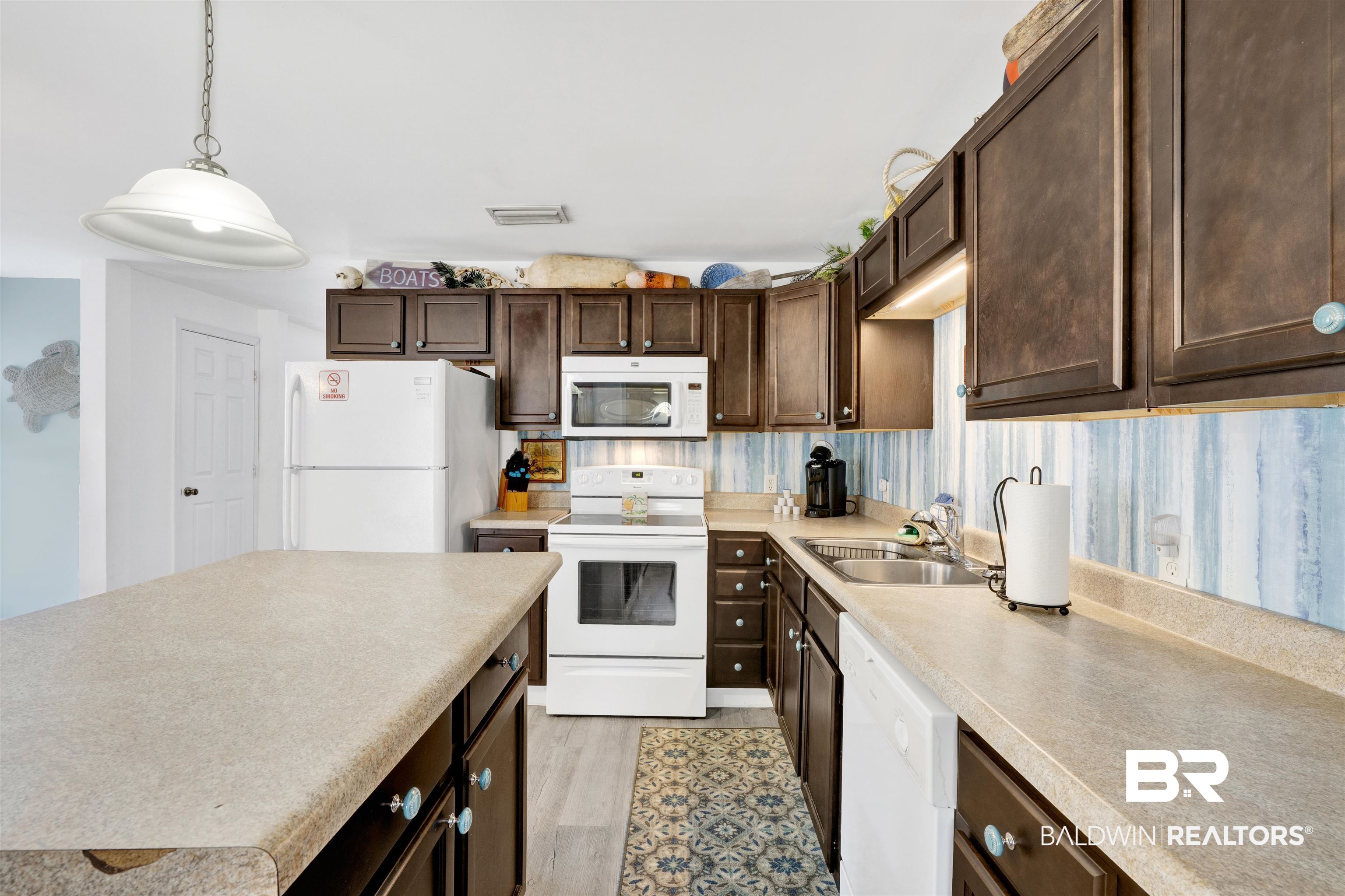 23770 Miflin Road Elberta, AL 36530 - Photo 10 of 38 Kitchen featuring dark brown cabinetry, white appliances, hanging light fixtures, light countertops, and light wood-style floors