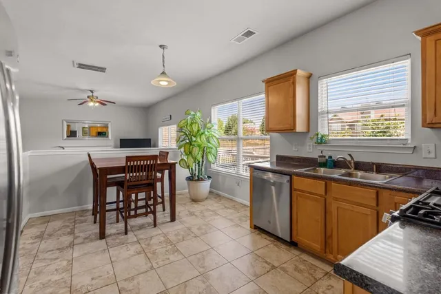 a kitchen with stainless steel appliances granite countertop a sink a stove a dining table and chairs