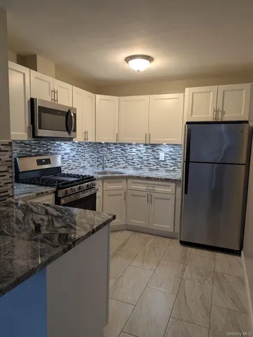 a kitchen with stainless steel appliances granite countertop a stove a sink dishwasher a refrigerator and a microwave