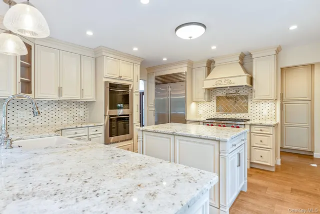 a kitchen with stainless steel appliances granite countertop a stove top oven a sink dishwasher and a refrigerator with wooden floor