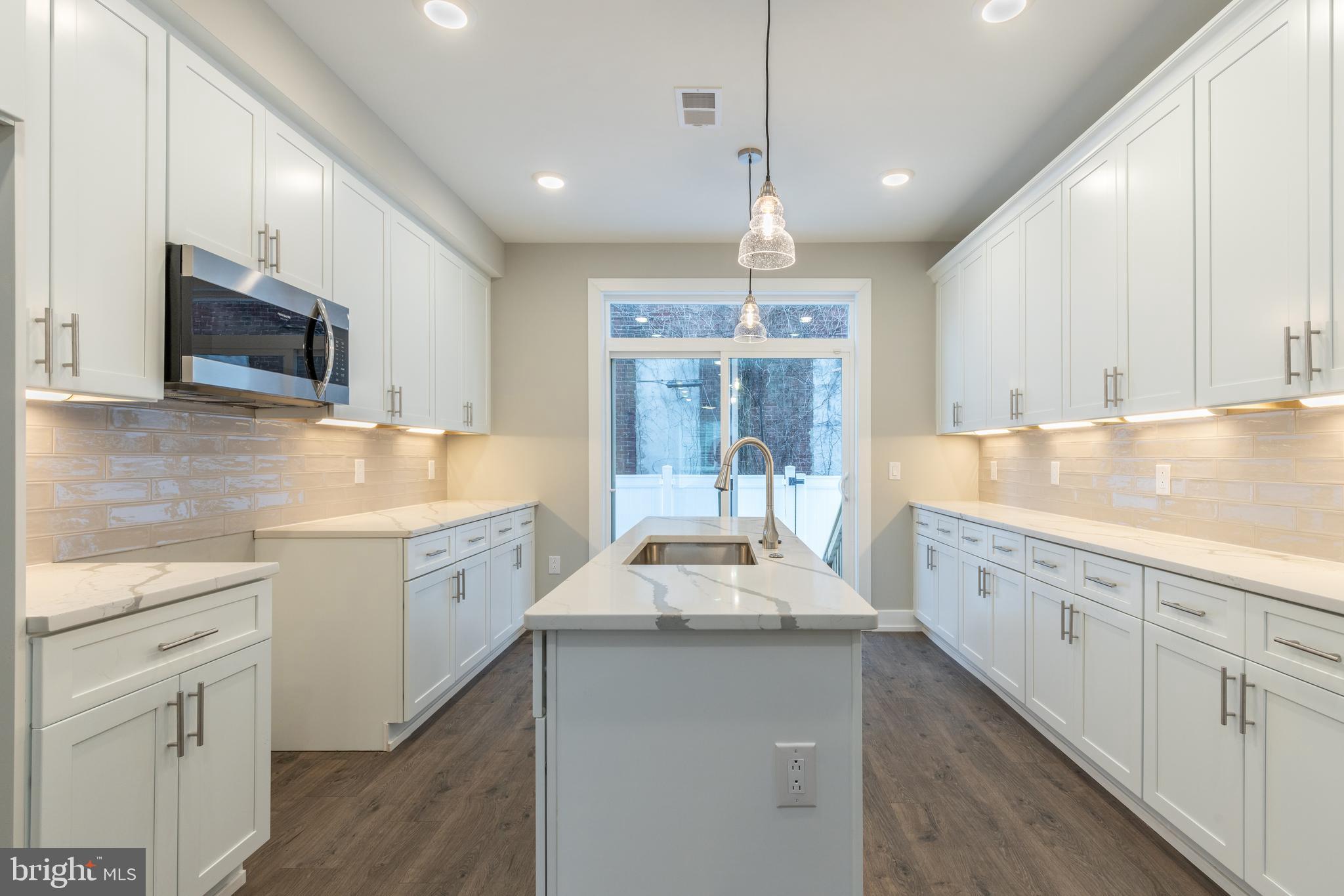 135 West Huntingdon Street, Unit 1 Philadelphia, PA 19133 - Photo 19 of 29 a large kitchen with stainless steel appliances kitchen island granite countertop a sink and cabinets